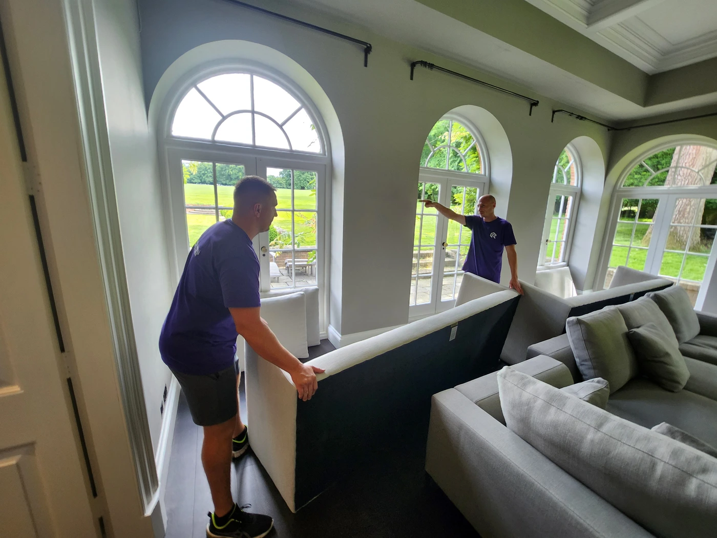 Two Rad Removals professionals placing furniture in an office, symbolizing the teamwork and coordination needed for a flawless office relocation